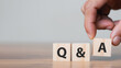 © Thapana_Studio - Hand holding Q and A words with wooden cube blocks , answers, ask questions, information,FAQ.