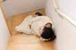 © SaitoFAM - A young pregnant Asian woman lies down on the stairs because of her labor pains