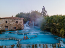 Natural Spa With Waterfalls And Hot Springs At Saturnia Thermal Baths, Grosseto, Tuscany, Italy,Hot Springs Cascate Del Mulino Man And Woman In Hot Spring Taking A Dip During Morning With Fog