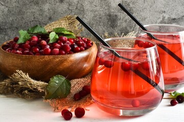 Two glasses Refreshing cocktail with cranberry and mint and bowl with cranberry, napkin on a white table. Selective focus