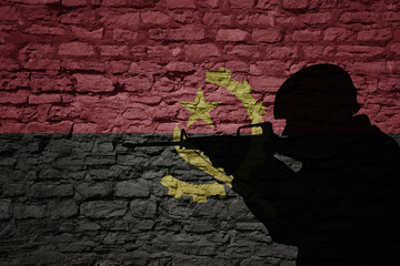 Wall Mural - Soldier silhouette on the old brick wall with flag of angola country.