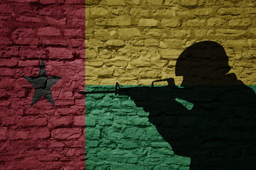 Wall Mural - Soldier silhouette on the old brick wall with flag of guinea bissau country.