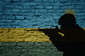 Wall Mural - Soldier silhouette on the old brick wall with flag of rwanda country.