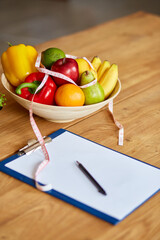 Top view of Nutritionist, dietitian workplace with measuring tape and bowl with healthy vegetables and fruits