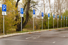 Parking In The City Park With Equipped Parking Spaces For Disabled People With Road Signs And Duplicated By Markings On The Asphalt. Perspective View On Row Of Parking Signs For Disabled People Only.