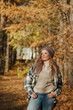 © KseniyaK - a blonde girl in a plaid shirt in the autumn forest