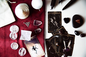 Altar with tarot cards on a burgundy scarf with several white quartz crystals, runes, black candles and selenite. Top view