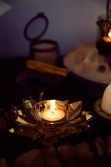 Wall Mural - Detail of a white candle on a golden flower-shaped candle holder, on a witch's altar to perform rituals.