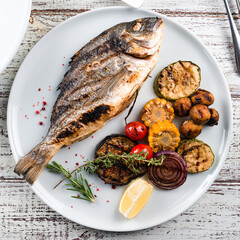 Poster - dorada grilled fish and vegetables on a plate top view, flat lay