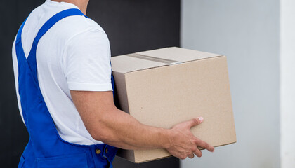 Wall Mural - Young delivery man hold a cardboard box in his hands