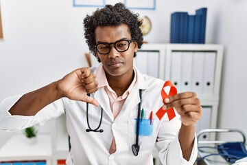 Sticker - African doctor man holding support red ribbon with angry face, negative sign showing dislike with thumbs down, rejection concept