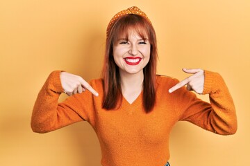 Wall Mural - Redhead young woman wearing casual orange sweater looking confident with smile on face, pointing oneself with fingers proud and happy.