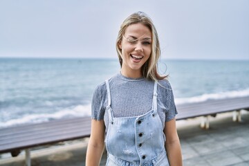 Poster - Young caucasian woman outdoors winking looking at the camera with sexy expression, cheerful and happy face.