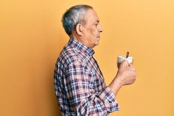 Canvas Print - Handsome senior man with grey hair drinking a cup coffee looking to side, relax profile pose with natural face and confident smile.