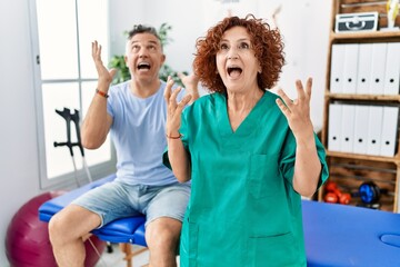 Poster - Physiotherapy woman working at pain recovery clinic with patient crazy and mad shouting and yelling with aggressive expression and arms raised. frustration concept.