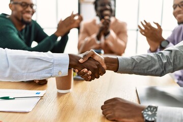 Sticker - Group of african american business workers smiling and clapping to partners handshake at the office.