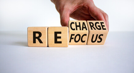 Wall Mural - Refocus and recharge symbol. Businessman turns cubes and changes the word 'refocus' to 'recharge'. Beautiful white table, white background. Business refocus and recharge concept. Copy space.