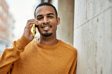 Wall Mural - Young african american man smiling happy talking on the smartphone at the city.