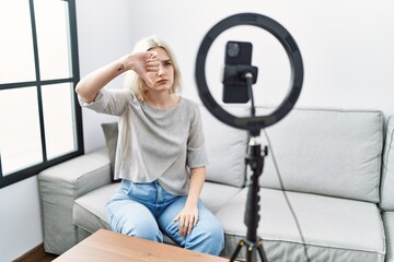 Poster - Young caucasian woman recording vlog tutorial with smartphone at home looking unhappy and angry showing rejection and negative with thumbs down gesture. bad expression.