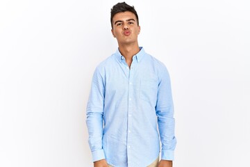 Canvas Print - Young hispanic man wearing business shirt standing over isolated background looking at the camera blowing a kiss on air being lovely and sexy. love expression.