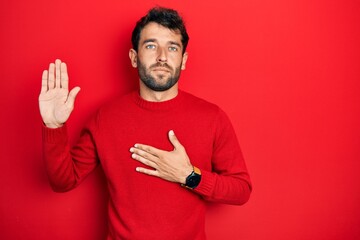 Poster - Handsome man with beard wearing casual red sweater swearing with hand on chest and open palm, making a loyalty promise oath