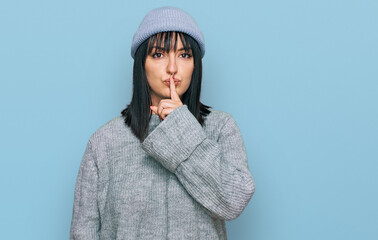 Canvas Print - Young hispanic woman wearing cute wool cap asking to be quiet with finger on lips. silence and secret concept.