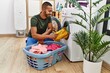 Young hispanic man cleaning clothes using washing machine at laundry