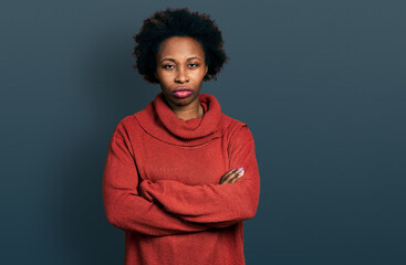 Poster - African american woman with afro hair wearing turtleneck sweater skeptic and nervous, disapproving expression on face with crossed arms. negative person.