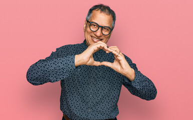 Sticker - Middle age indian man wearing casual clothes and glasses smiling in love doing heart symbol shape with hands. romantic concept.