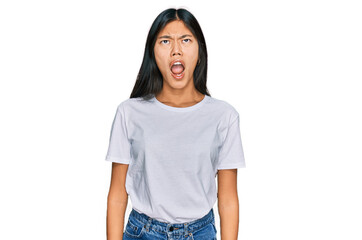 Poster - Beautiful young asian woman wearing casual white t shirt angry and mad screaming frustrated and furious, shouting with anger. rage and aggressive concept.