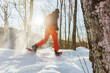 © Maridav - Snowshoeing outdoor winter fitness activity happy man running in snowshoes in snow from behind in sunny forest landscape.