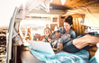 Digital nomad couple traveling together with dog on retro van transport - Freedom life style concept with indie people on minivan adventure sharing content using notebook - Warm backlight filter