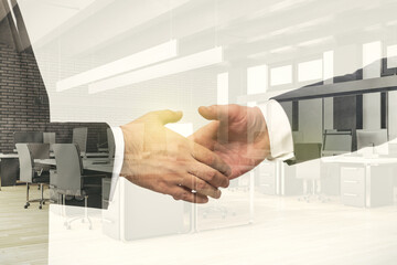 Double exposure handshake of two businessmen on modern furnished office interior background, collaboration and coworking concept