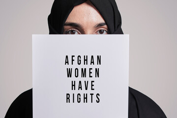 Muslim woman holding a paper with text - Afghan women have rights. Muslim woman in traditional hijab clothing. Domestic violence, discrimination of Muslim women