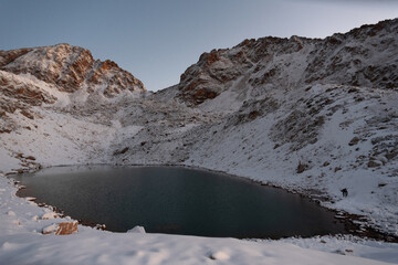 Canvas Print - High mountain lake with mountain peaks covered with snow at sunrise