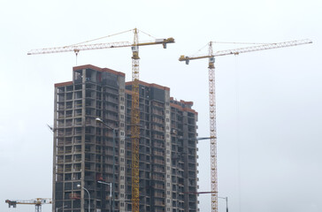 Wall Mural - Tower cranes at the construction site of a multi-storey building.