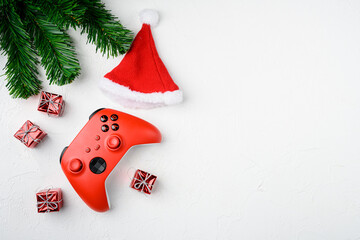 Red gamepad among Christmas tree toys, on white stone table background, top view flat lay, with copy space for text