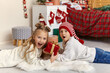 © Inna Vlasova - Cheerful little brother and sister lie on the floor hold gift box