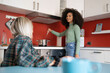 © Lomb - Two young multiracial students girls cooking in the youth hostel kitchen talking an socializing together