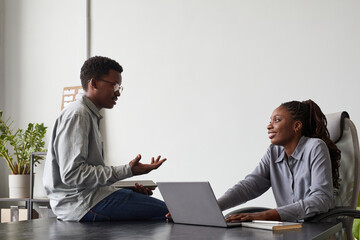 Wall Mural - minimal side view portrait of two african-american young people chatting in office while discussing 