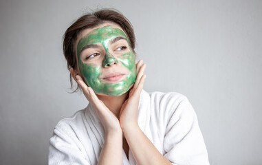 Wall Mural - Attractive young woman with a green cosmetic mask on her face.