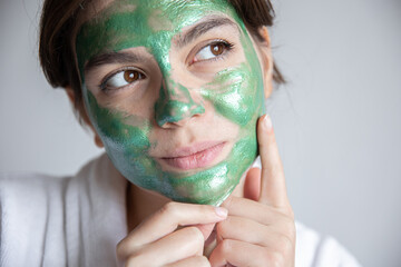 Wall Mural - Attractive young woman with a green cosmetic mask on her face.