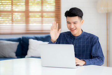 Wall Mural - Young asian business man using laptop computer for video call online hello and communicate work from home, male conference with notebook and say hi, social distancing, communication concept.