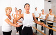 © JackF - Women of different ages standing in row and training ballet moves. Their senior trainer correcting them.
