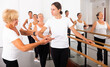 © JackF - Dancing women engaged in classical ballet at a group training session in the studio stand in a ballet stance, where the ..choreographer helps to coordinate the movement correctly