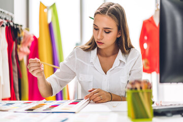 Wall Mural - Portrait of young beautiful pretty owner business woman fashion designer stylish sitting and working.Attractive young designer girl use desktop conputer and colorful fabrics at fashion design workshop