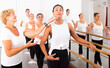 © JackF - Dancing Asian woman doing ballet in a female group in the studio is standing in a ballet stance, where the choreographer ..helps to perform the exercise correctly