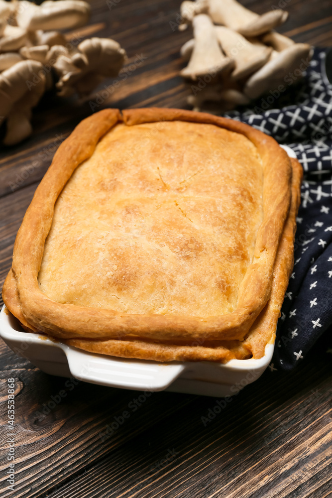 Baking dish with tasty mushroom pot pie on wooden background