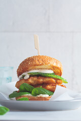 Canvas Print - Fish burger on a gray plate. Cod fish in batter with mayonnaise and spinach sandwich.