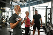 © Svitlana - Approachable trainer supporting elderly couple while gym workout